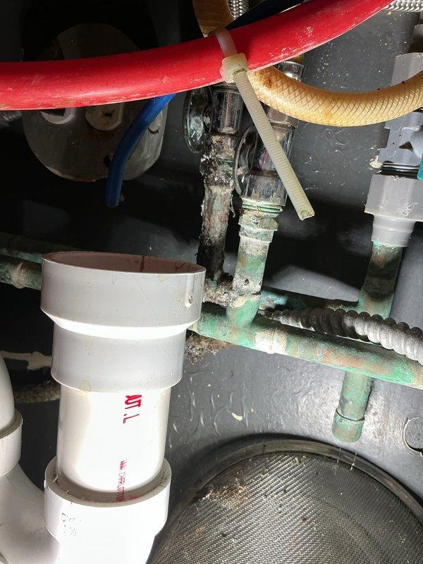 Responded to emergency commercial plumbing call for leaking faucet requiring repair prior to scheduled inspection. Upon arrival, inspected commercial double-basin stainless steel sink with integrated eyewash station and identified leak source in the plumbing assembly beneath the fixture. Accessed confined mechanical space and examined complex pipe configuration including PEX lines, corrugated flexible hoses, PVC drainage pipes, and corroded metal supply lines showing significant mineral deposits and surface deterioration. Repaired faulty connection, tested eyewash station functionality, verified proper water flow to both faucet handles, and ensured all components were operational and leak-free in preparation for inspection compliance.