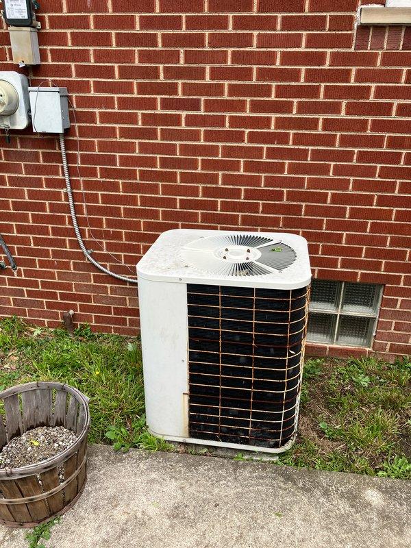 Responded to service call for 17-year-old furnace system not heating and blowing cold air. Upon inspection, diagnosed failed heat exchanger and defective gas valve in basement-located unit. Provided comprehensive estimate for complete HVAC system replacement including new furnace and outdoor condensing unit. Documented existing equipment condition showing weathered outdoor unit on concrete pad against building foundation with proper electrical disconnect and conduit installation. Customer advised of safety concerns with failed heat exchanger and recommended full system replacement due to age and extent of required repairs.