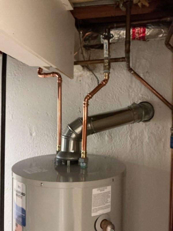 Completed installation of residential tanked water heater in utility room. Connected copper supply lines with brass fittings to unit, installed exhaust venting system with proper pitch and termination, and verified all connections for code compliance. Mounted temperature and pressure relief valve, installed drain pan safety sensor with monitoring device secured to discharge pipe, and set temperature controls to manufacturer specifications. All plumbing connections pressure tested and system commissioned successfully with hot water delivery confirmed throughout residence.