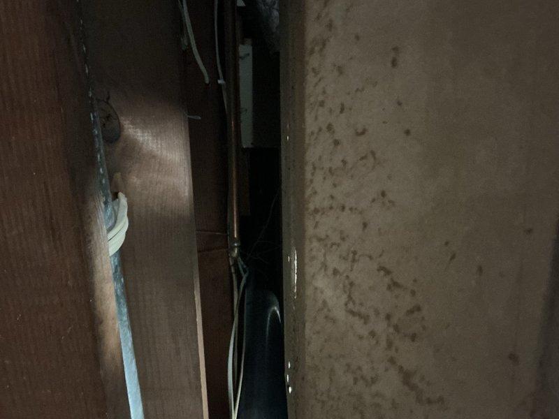 Responded to emergency call for burst pipes in basement caused by freezing conditions. Upon arrival, conducted thorough inspection of affected area and documented damage to plumbing infrastructure. Multiple frozen pipes had ruptured, resulting in water damage to basement ceiling and surrounding structural components. Photographed exposed ceiling cavity showing damaged pipe sections, wooden support beams, and affected building materials. Documented water intrusion points and extent of damage to acoustic ceiling tiles and adjacent wall surfaces. Assessed basement utility area where burst pipes were located, noting water damage patterns on concrete walls and floors. Provided comprehensive visual documentation of all damaged components for insurance claim purposes, including detailed photographs of compromised plumbing system and resulting structural impact.
