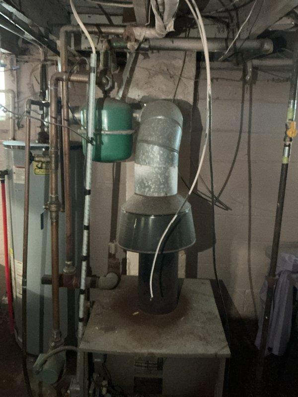 Conducted site assessment for new boiler installation in basement mechanical room to replace existing 15-year-old unit. Documented current system configuration including existing heating equipment, water heater, expansion tank, and associated piping infrastructure. Photographed mechanical room layout, equipment placement, existing ductwork assembly, copper and PVC piping runs, electrical connections, and clearance requirements for proper sizing and installation planning of replacement boiler system.