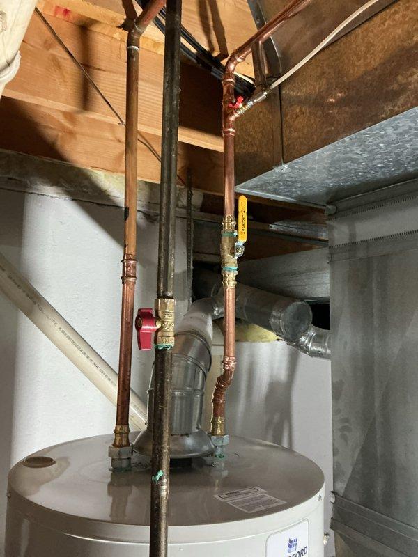 Completed installation of a 50-gallon Bradford White tanked water heater in basement utility area. Configured copper supply piping with brass shut-off valves, installed expansion tank, and connected flexible gas line to unit. All plumbing connections were properly secured and tested to ensure system functionality and code compliance.