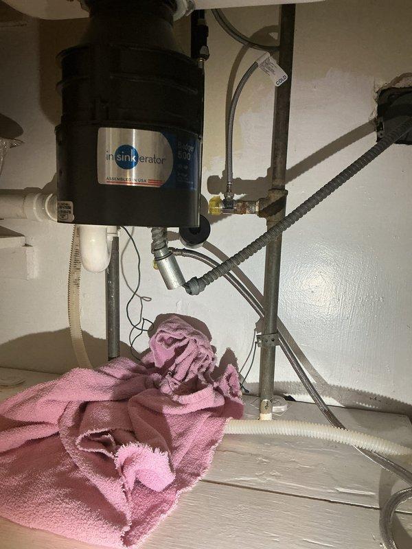 Replaced existing valve under kitchen sink to accommodate new dishwasher installation. Verified proper connections to InSinkErator garbage disposal unit, confirmed all PVC drain lines and P-trap assembly were secure, and tested water supply lines for leaks. Installation now ready for dishwasher hookup.