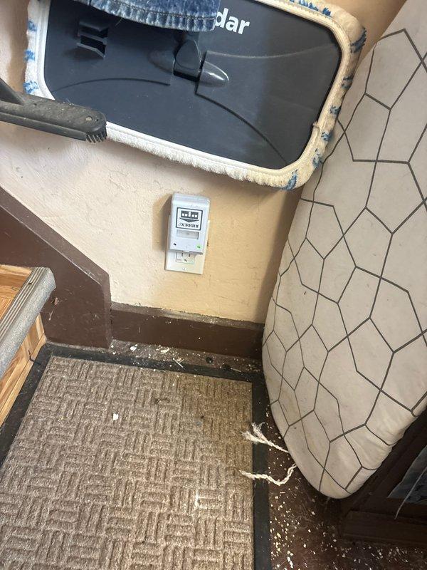 Completed electrical outlet installation and repair in kitchen area with distressed wood paneling. Relocated and secured outlet box to meet code requirements, ensuring proper grounding and connection integrity. Addressed wall deterioration issues around thermostat/control device mounting area, secured electrical components, and verified all connections were functioning safely despite compromised wall conditions.