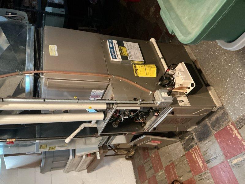 Completed comprehensive Gold AC inspection on 14-year-old residential HVAC system located in basement utility area. Performed thorough visual examination of air handler unit, refrigerant lines, electrical connections, and control components. Inspected copper tubing for proper insulation, verified ductwork connections, and assessed overall system condition. Documented equipment with photographs showing air handler, refrigerant piping, electrical wiring, and associated mechanical components. System confirmed operational at time of inspection. All accessible components examined and found to be functioning within normal parameters for equipment age.