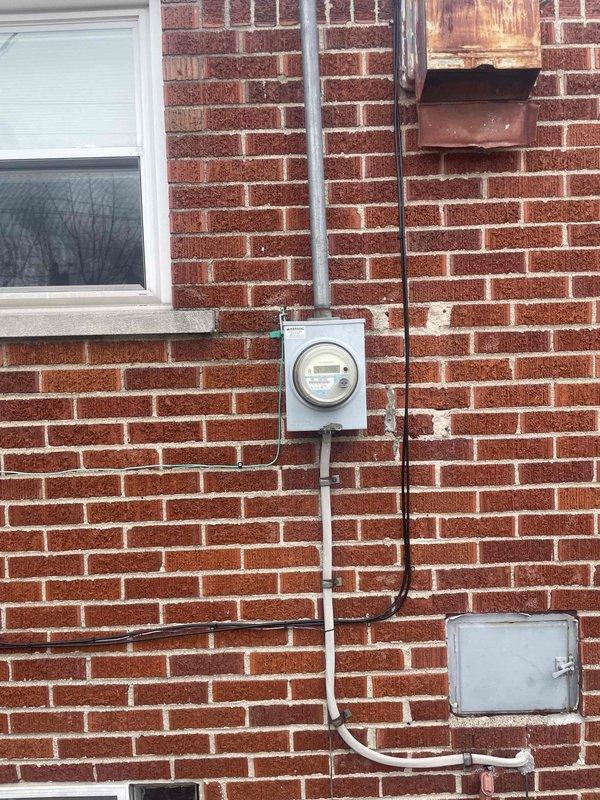 Conducted site evaluation for AC replacement estimate at residential property with outdoor unit located in backyard. Assessed existing HVAC system including basement-mounted furnace with air handler, ductwork configuration, and exterior electrical service connections. Documented current equipment condition, refrigerant line routing, and electrical disconnect panel mounted on exterior brick wall to determine replacement specifications and installation requirements for new air conditioning system.