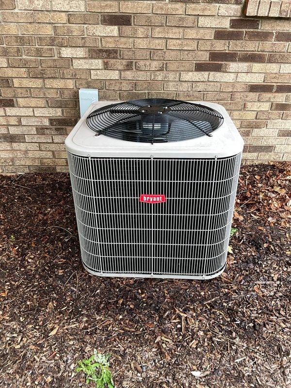 Completed Gold AC Inspection on 16-year-old Bryant air conditioning system with outdoor condenser unit and basement-located air handler. Performed comprehensive multi-point inspection including visual examination of condenser unit exterior condition, capacitor assessment showing P291-4575 MFD rated component at 370V, electrical connection verification of all wiring terminals, and airflow evaluation through condenser grille. Documented equipment condition with photographic evidence showing unit positioned on mulch ground cover against exterior brick wall with fan assembly and protective wire guard intact. Verified system operational status with homeowner, confirmed single-zone configuration, and completed standard maintenance protocol for residential cooling equipment. All components inspected and found functional at time of service.