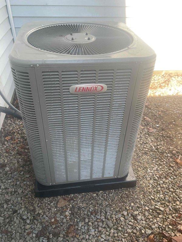 Completed comprehensive Gold AC inspection on 2-year-old Lennox system with air handler located in laundry room. Inspected outdoor condenser unit, noting dirt and debris accumulation on coil fins requiring attention, verified system operational status, and documented equipment condition through photographic records. Unit confirmed functioning properly with homeowner present, condenser positioned on proper pad with adequate clearance from structure.