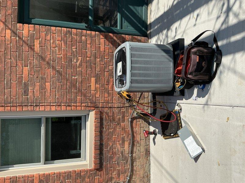 Relocated air conditioning condenser unit to new position on exterior concrete pad. Reinstalled refrigerant line set through wall penetration with proper grommet and seal, performed system pressure test with manifold gauges, and verified unit operation at new location.
