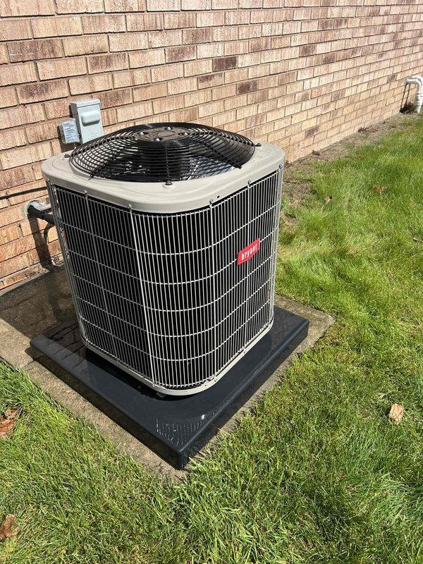 Completed comprehensive Gold AC inspection on 13-year-old residential HVAC system with furnace located in basement. Performed thorough evaluation of outdoor condenser unit positioned on isolation pad against exterior brick wall, inspecting cylindrical unit with vertical grille fins and top-mounted fan assembly. Verified proper operation of all electrical components including dual run capacitor assembly, contactor relay unit, and associated wiring connections with multiple colored conductors. Inspected refrigerant line set routing along exterior wall to disconnect box penetration point. All electrical terminals, spade connectors, and control circuits examined for proper connections and signs of wear. System operating within normal parameters with no immediate service needs identified. Documented equipment condition through photographic records showing capacitor assembly, contactor unit, and exterior condenser placement. Unit showing age-appropriate wear with minor dust accumulation on e