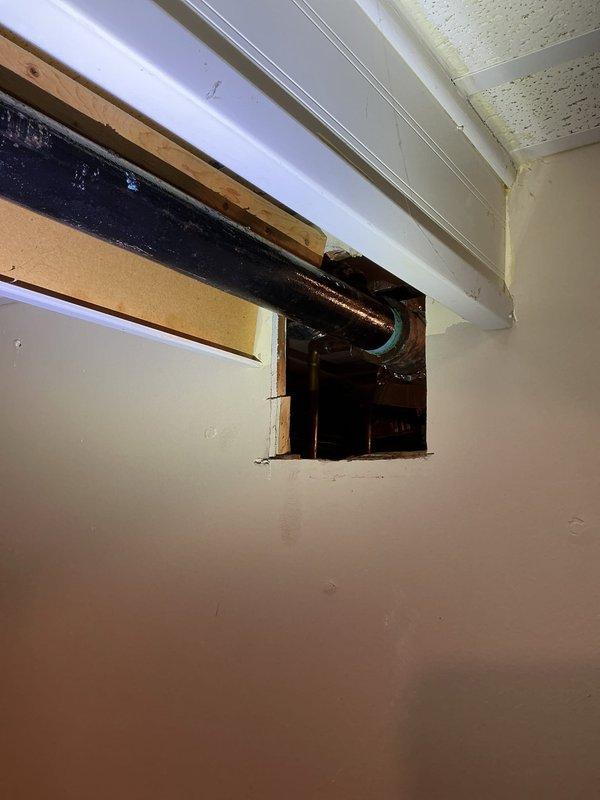 Accessed plumbing infrastructure through wall and ceiling openings to repair and replace damaged piping sections. Installed new black plastic pipe with compression fittings to address leak in horizontal supply line running above kitchen ceiling. Replaced corroded copper piping that exhibited green patina deterioration with modern plastic piping system, ensuring proper connections and secure mounting to structural framing members.