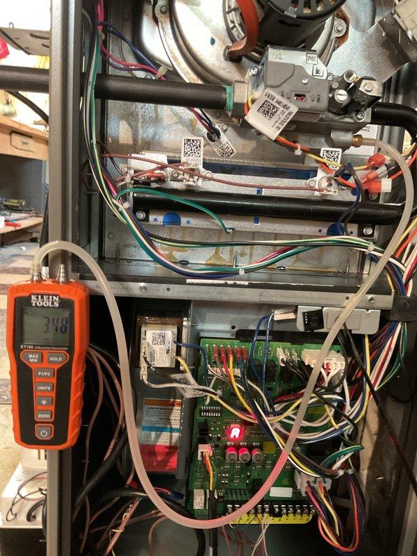 Completed AC system startup and commissioning for basement installation. Performed comprehensive diagnostics using digital manometer to verify static pressure readings at 2.13 inches w.c., confirming proper airflow and duct system performance. Verified electrical system operation with multimeter reading 248 volts, checked all control board functions including LED indicators, and confirmed proper wiring connections throughout the unit. All components operating within manufacturer specifications.