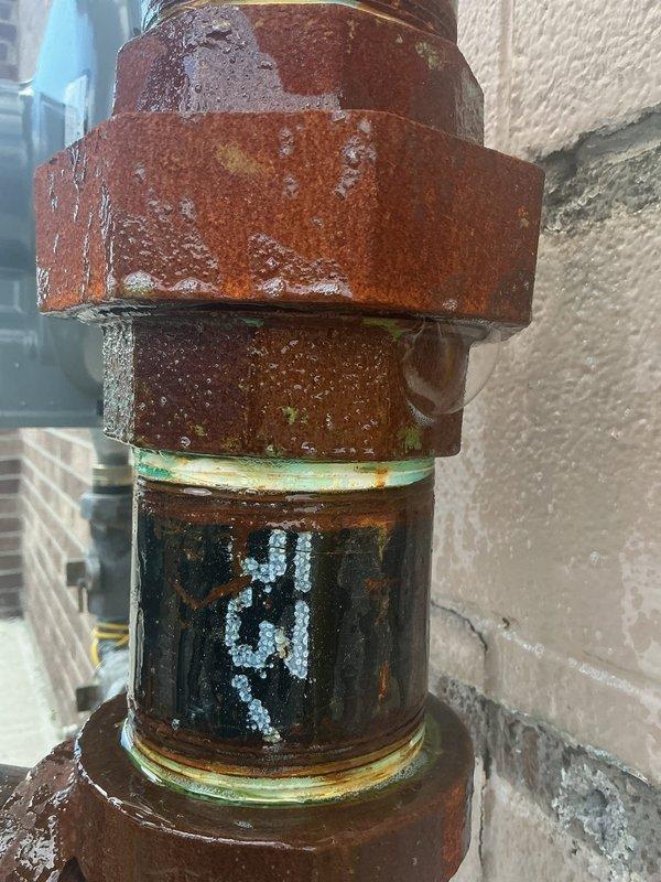 Responded to gas leak identified by utility company on commercial gas line installation. Located two leaking threaded fittings on south side of building past the meter at line connection point. Repaired corroded pipe fittings and unions showing extensive weathering and surface oxidation. Performed pressure test to verify system integrity and confirm leak elimination. Completed required utility company documentation and removed caution tag upon successful repair verification.