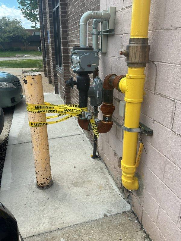 Responded to gas leak identified by utility company on commercial gas line installation. Located two leaking threaded fittings on south side of building past the meter at line connection point. Repaired corroded pipe fittings and unions showing extensive weathering and surface oxidation. Performed pressure test to verify system integrity and confirm leak elimination. Completed required utility company documentation and removed caution tag upon successful repair verification.