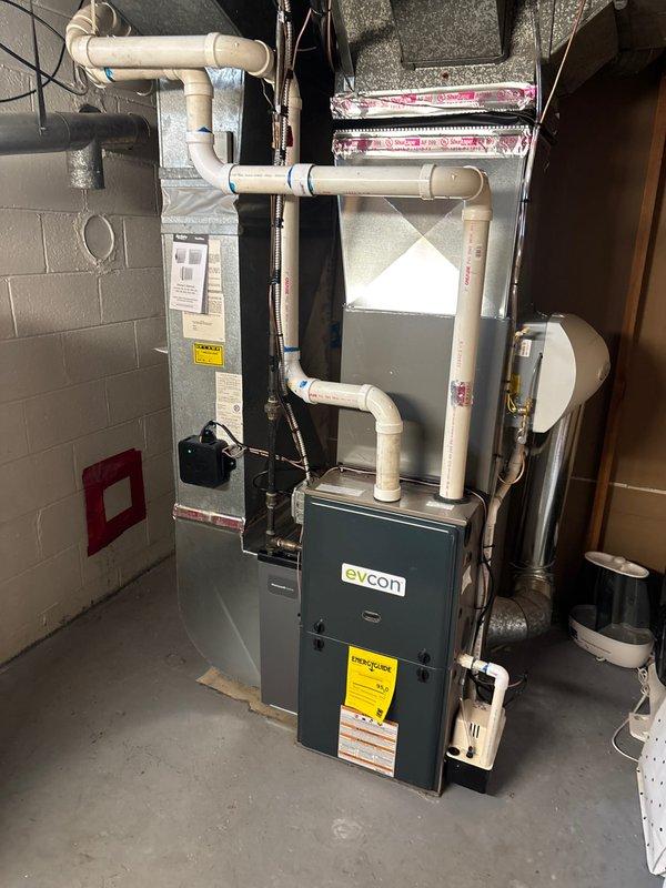 Completed installation of new air conditioning system and evaporator coil in basement utility area, including furnace integration, condensate drainage lines with PVC piping, and ductwork modifications. Coordinated permit request and identified electrical work requirement for final system connection. Equipment remeasurement performed due to late specification changes to ensure proper sizing and fit.