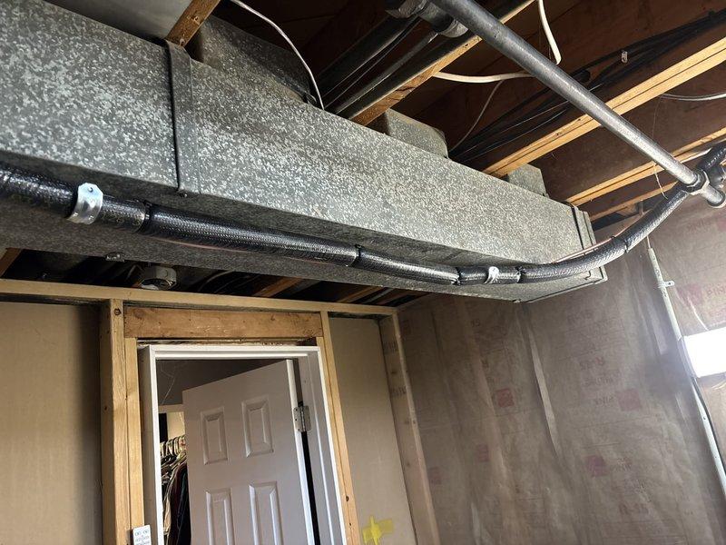 Completed installation of new air conditioning system and evaporator coil in basement utility area, including furnace integration, condensate drainage lines with PVC piping, and ductwork modifications. Coordinated permit request and identified electrical work requirement for final system connection. Equipment remeasurement performed due to late specification changes to ensure proper sizing and fit.