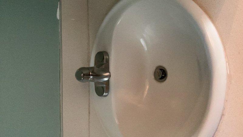 Completed conversion of bathtub drain assembly from trip lever style to lift-and-turn type mechanism. Replaced existing half bath faucet with new fixture, including installation of brushed metal cross-handle faucet assembly on bathroom sink. Inspected existing shower/tub area, noting significant deterioration of fiberglass surface coating with extensive peeling and exposure of underlayer material. Verified proper operation of all new components and confirmed drainage function on both fixtures.