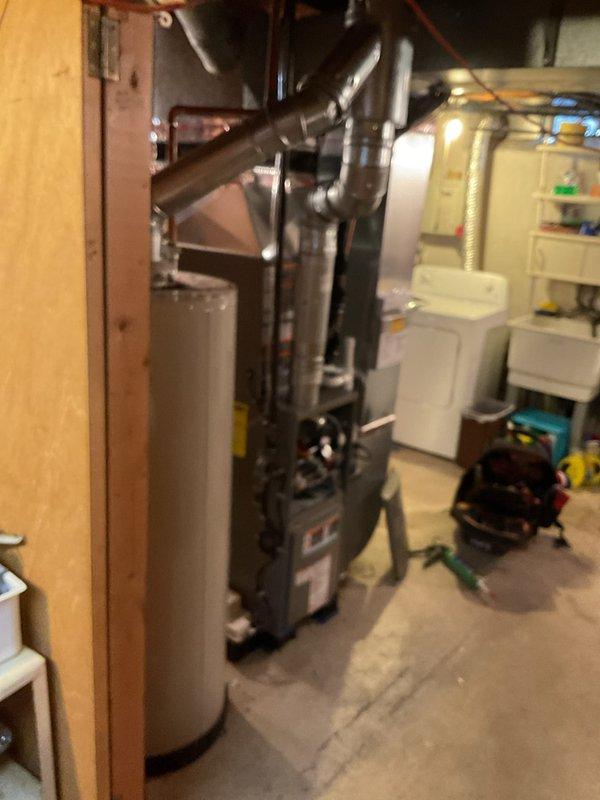 Completed full HVAC system installation in basement mechanical room, including 70,000 BTU furnace and 2-ton air conditioning unit with rear discharge configuration. Installed new furnace with proper venting and ductwork connections, positioned adjacent to existing water heater. Connected AC system with metallic ductwork routing, including S-curved supply duct transitioning to overhead distribution system. Ran all necessary gas lines, electrical connections, and refrigerant lines per code requirements. Secured all mechanical, electrical, and HVAC permits prior to installation. Reconnected all utility services and verified proper operation of both heating and cooling systems. System tested and confirmed operational with all safety controls functioning correctly.