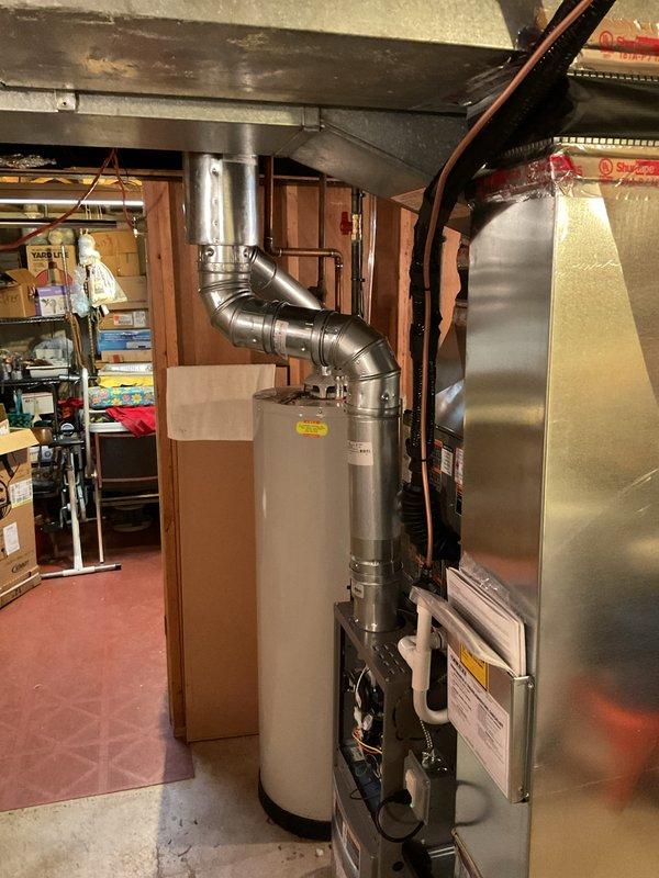 Completed full HVAC system installation in basement mechanical room, including 70,000 BTU furnace and 2-ton air conditioning unit with rear discharge configuration. Installed new furnace with proper venting and ductwork connections, positioned adjacent to existing water heater. Connected AC system with metallic ductwork routing, including S-curved supply duct transitioning to overhead distribution system. Ran all necessary gas lines, electrical connections, and refrigerant lines per code requirements. Secured all mechanical, electrical, and HVAC permits prior to installation. Reconnected all utility services and verified proper operation of both heating and cooling systems. System tested and confirmed operational with all safety controls functioning correctly.