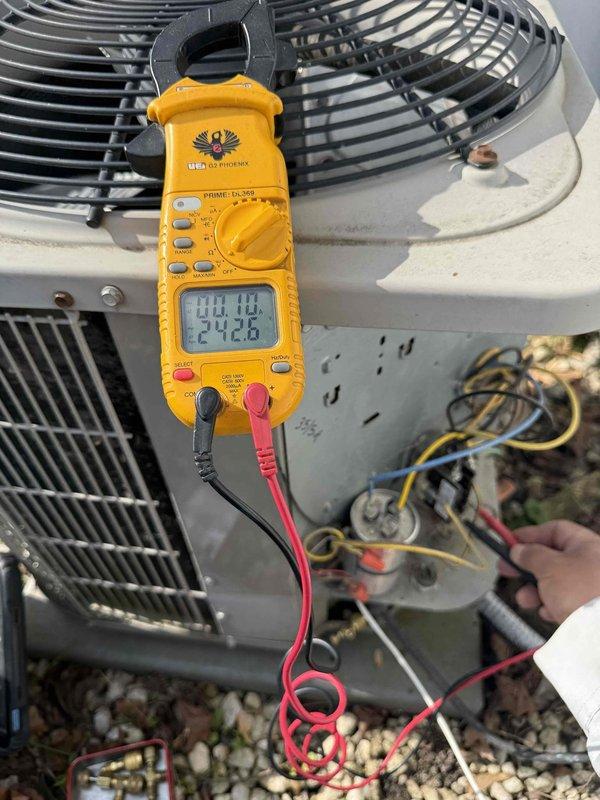 Completed comprehensive Gold AC Inspection on 10-year-old residential air conditioning system with air handler located in basement. Performed electrical diagnostics using clamp meter, measuring voltage at 242.4-242.8V and amperage at 0.18A at outdoor condenser unit. Inspected condenser coils, fan assembly, capacitor, and all electrical connections for proper operation. Advised property owner that condenser area requires clearing of debris and animal waste for optimal system performance, and that additional inspection is scheduled for second property location.