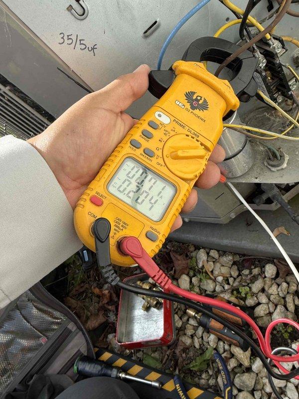 Completed comprehensive Gold AC Inspection on 10-year-old residential air conditioning system with air handler located in basement. Performed electrical diagnostics using clamp meter, measuring voltage at 242.4-242.8V and amperage at 0.18A at outdoor condenser unit. Inspected condenser coils, fan assembly, capacitor, and all electrical connections for proper operation. Advised property owner that condenser area requires clearing of debris and animal waste for optimal system performance, and that additional inspection is scheduled for second property location.