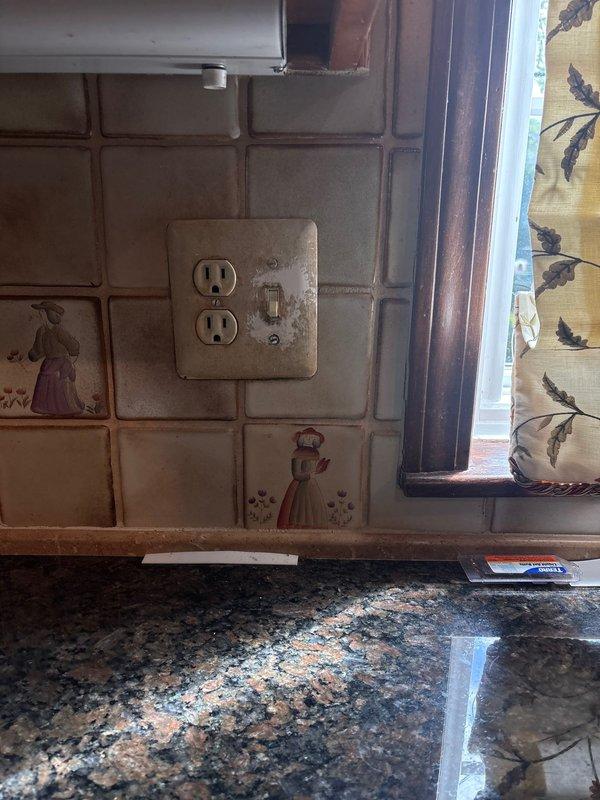 Responded to service call for non-functioning garbage disposal and problematic switch. Performed electrical diagnostics and testing of kitchen outlet circuits using digital voltage tester, confirming proper 124 VAC power supply and correct wiring at receptacle locations. Inspected switch controlling garbage disposal unit and associated electrical connections in kitchen area with decorative tile backsplash. Verified circuit integrity and proper grounding throughout affected areas.