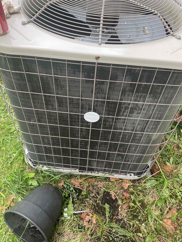 Performed comprehensive tune-up on 2006 air conditioning condenser unit located in crawlspace area. Inspection included thorough evaluation of outdoor condenser unit showing weathered conditions with dirt accumulation on front grille and vegetation growth around base. Checked and assessed humidifier, thermostat, and hot water tank as part of complete system evaluation. Unit operational with noted exterior wear consistent with age and outdoor exposure.