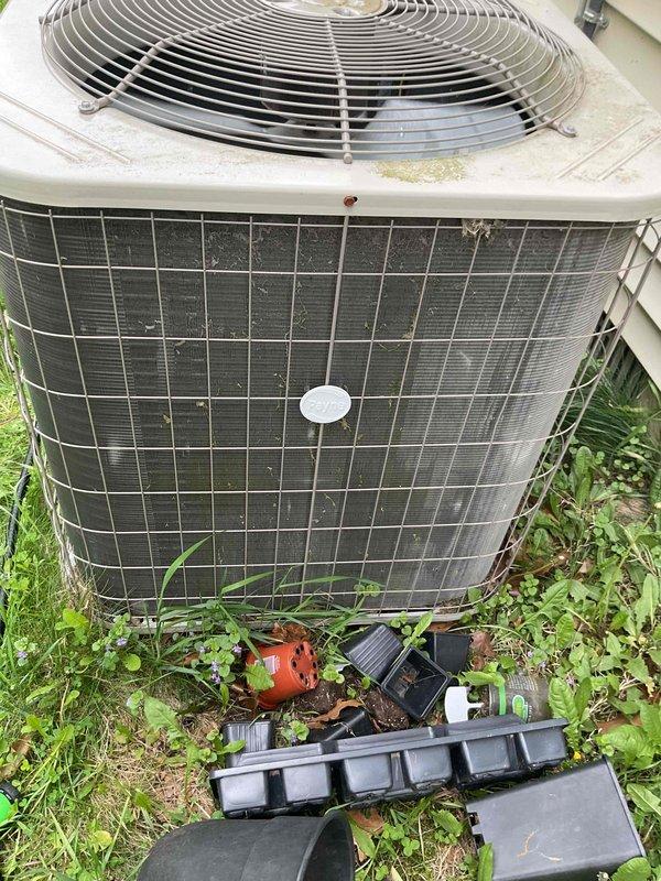 Performed comprehensive tune-up on 2006 air conditioning condenser unit located in crawlspace area. Inspection included thorough evaluation of outdoor condenser unit showing weathered conditions with dirt accumulation on front grille and vegetation growth around base. Checked and assessed humidifier, thermostat, and hot water tank as part of complete system evaluation. Unit operational with noted exterior wear consistent with age and outdoor exposure.