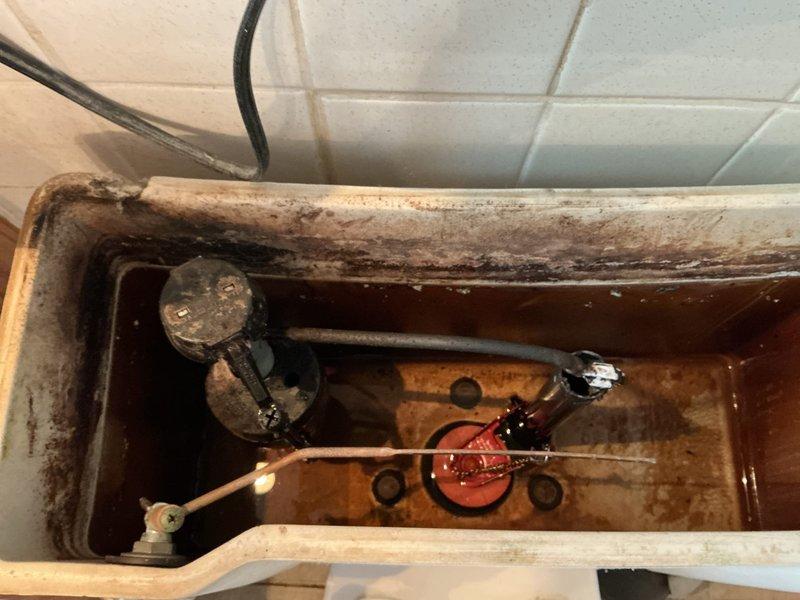 Responded to service call for toilet not flushing or receiving water. Upon inspection, found heavily stained toilet tank with significant mineral deposits and rust-colored buildup throughout interior surfaces. Fill valve assembly displayed extensive corrosion and mineral accumulation affecting water flow. Replaced deteriorated fill valve and corroded flush valve components. Installed new flapper seal to restore proper flush function. Tested system operation and confirmed toilet now filling and flushing properly with adequate water supply restored.