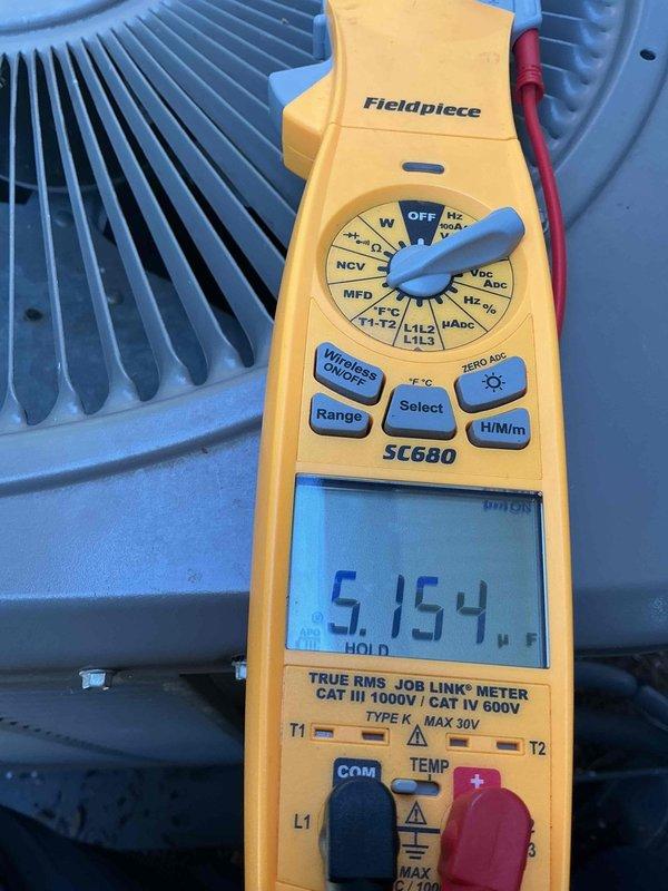 Completed Gold AC Inspection on a three-unit residential HVAC system with equipment under 10 years old. Two air handlers located in basement and one in attic were inspected and found to be operating within normal parameters. Performed comprehensive electrical diagnostics using calibrated multimeter, recording voltage readings of 247.9V AC at outdoor condensers, confirming proper power supply to all units. Measured capacitor values reading 5.154 MFD on system components, verifying electrical components are functioning correctly. Visually inspected condenser coils on all three outdoor units, confirming fins are clean and free from debris with adequate airflow. All three systems passed inspection with no immediate service needs identified and are operating as designed.