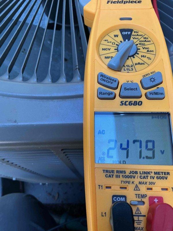 Completed Gold AC Inspection on a three-unit residential HVAC system with equipment under 10 years old. Two air handlers located in basement and one in attic were inspected and found to be operating within normal parameters. Performed comprehensive electrical diagnostics using calibrated multimeter, recording voltage readings of 247.9V AC at outdoor condensers, confirming proper power supply to all units. Measured capacitor values reading 5.154 MFD on system components, verifying electrical components are functioning correctly. Visually inspected condenser coils on all three outdoor units, confirming fins are clean and free from debris with adequate airflow. All three systems passed inspection with no immediate service needs identified and are operating as designed.