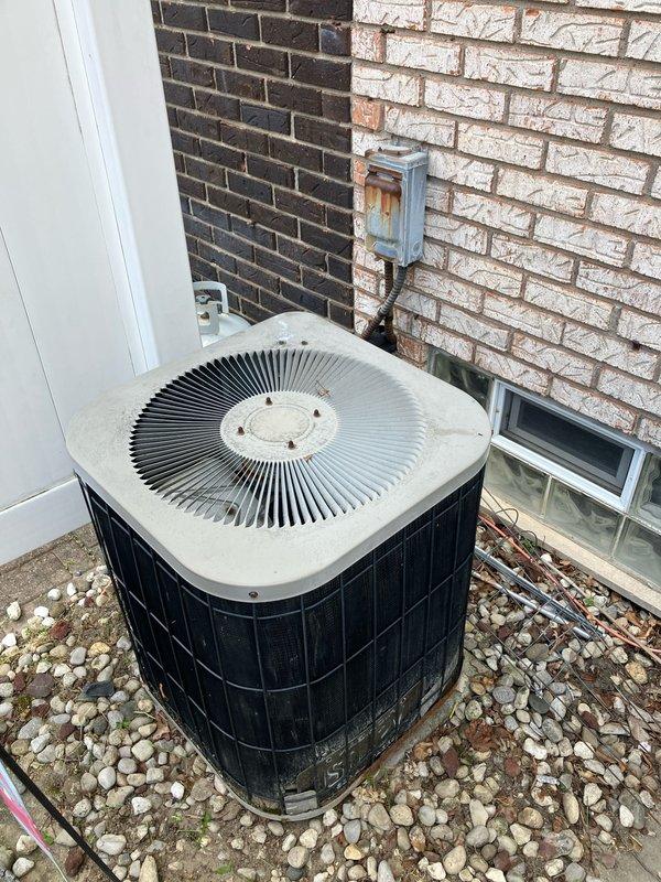 Conducted comprehensive evaluation of existing 25-year-old residential HVAC system for full replacement estimate. Assessed gas furnace located in basement, currently operational, and outdoor air conditioning condenser unit with distinctive circular fan configuration positioned on concrete pad with decorative rock landscaping against exterior brick wall. Documented existing system components including ductwork connections, copper refrigerant lines, and electrical service. Photographed condenser unit showing age-related wear and basement furnace installation with metal supply duct transitions and piping connections. Provided customer with complete system replacement options for both heating and cooling equipment based on current system age and configuration.