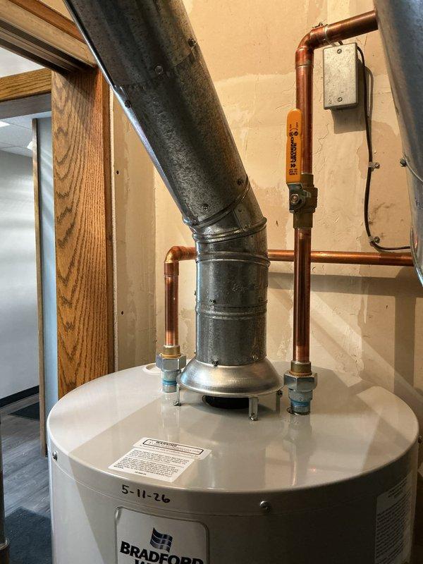 Completed installation of 40-gallon Bradford White commercial-grade tanked water heater in utility area. Connected all copper supply lines, installed required safety valves and shutoffs, and properly vented unit with metal flue pipe to ensure code compliance and safe operation.