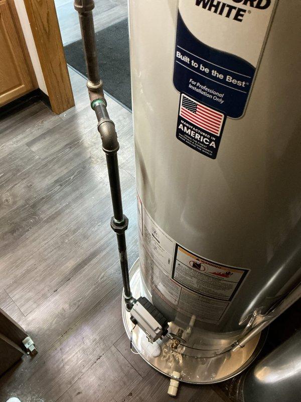 Completed installation of 40-gallon Bradford White commercial-grade tanked water heater in utility area. Connected all copper supply lines, installed required safety valves and shutoffs, and properly vented unit with metal flue pipe to ensure code compliance and safe operation.