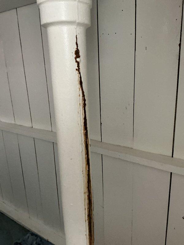 # Emergency Plumbing Repair - Basement Pipe Leak

Responded to an active water leak in the basement caused by a cracked vertical PVC drain pipe. Upon arrival, discovered a significant vertical split running along the length of the pipe with heavy rust-colored staining indicating ongoing water seepage. Temporary measures were implemented by placing absorbent towels at the base of the pipe to contain water damage to the basement floor area.

Documented the extent of the damage through photographic evidence, capturing the crack location at the coupling joint and the rust discoloration pattern. The pipe showed signs of deterioration with metal corrosion visible within the PVC system, suggesting contamination or internal component failure. The leak was confined to the basement utility area with no indication of spread to upper floors at the time of service.

Assessed the vertical pipe running from floor to ceiling and identified the compromised section requiring replacement. The rust staini