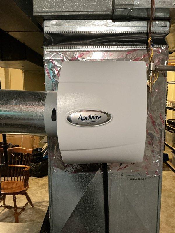Completed comprehensive Gold AC Inspection on residential HVAC system with air handler located in basement. Performed thorough evaluation of cooling equipment, ductwork, and associated components including whole-house Aprilaire humidifier integrated into the system. Inspected exterior condensing unit mounted on brick foundation, examining electrical connections, conduit routing, and unit mounting. All equipment found operational with no immediate service concerns identified during inspection.