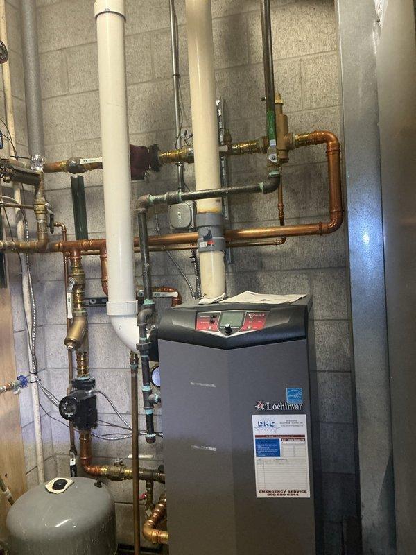 Responded to service call for overheating issue with hydronic heating system serving three air handlers. Diagnosed malfunctioning boiler system unable to respond to thermostat commands, resulting in excessive heat output throughout residence. Upon inspection of 10+ year old Lochinvar boiler unit located in basement, identified failed pressure check valves preventing proper system regulation and temperature control. Thermostat displaying abnormal readings of 195% and failing to communicate effectively with boiler controls. Documented existing piping configuration including copper supply and return lines, PVC venting, expansion tank, and multiple zone valves. Ordered replacement pressure check valves for installation upon arrival at shop. System temporarily assessed pending parts delivery to restore proper thermostatic control and resolve overheating condition.