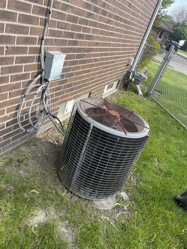 Provided comprehensive estimate for complete air conditioning system replacement of 25-year-old outdoor unit that ceased operation last year. Unit located on side of house shows significant weathering, age-related deterioration, and discoloration on exterior surfaces. Assessed existing installation including copper refrigerant lines, electrical disconnect box, mounting pad condition, and associated electrical conduit system for replacement planning considerations.