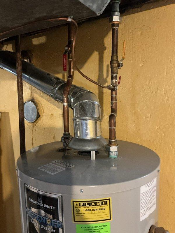 Responded to service call for reported leak on hot water line at water heater installed November 2021 under active warranty. Upon arrival, performed thorough diagnostic inspection of water heater and associated copper piping connections. Examined top-mounted heat trap assembly, hot water outlet connections, and all visible copper pipe joints for signs of active leakage or moisture accumulation. Inspected flexible duct connector and surrounding mechanical components in utility area. Verified integrity of pipe fittings, including white plastic clamps and galvanized metal connections at tank crown. Assessed condition of all accessible plumbing connections and determined source of reported leak for appropriate corrective action.