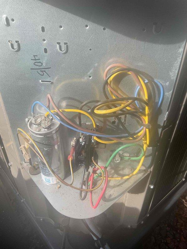 Completed comprehensive Gold AC inspection on a 10-year-old residential air conditioning system. Unit confirmed operational at time of service. Performed thorough examination of outdoor condenser unit positioned against building exterior, noting standard wear consistent with age. Inspected electrical components including capacitor, wiring connections, and terminal blocks within unit compartment. All color-coded wiring and electrical connections verified secure and properly configured. Condenser unit exterior housing and fan grille inspected with no significant damage observed. Unit mounted on appropriate base pad with proper clearance from landscaping. Refrigerant lines and electrical conduit connections checked for integrity. System components photographed for service records.