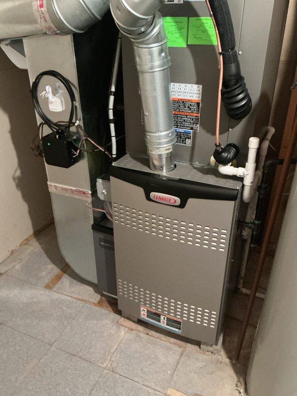Completed air conditioning system startup for newly installed Lennox EL16KC1-042-230A02 condensing unit with R-410a refrigerant and matching indoor evaporator coil. Verified proper electrical connections at 208/230V single-phase power supply, confirmed compressor RLA of 17.3 amps and LRA of 123 amps within specifications, and tested 1/4 HP condenser fan motor operation. Inspected refrigerant line set connections between outdoor unit and basement-installed air handler, checked factory refrigerant charge, and verified system pressures. Confirmed proper condensate drainage through white PVC piping, tested all safety controls and warning labels, and validated ductwork connections to furnace plenum. System operating efficiently with all components functioning as designed.