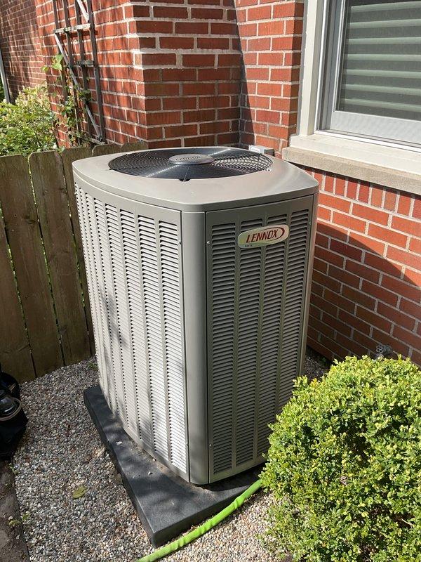 Completed Gold AC Inspection on a Lennox outdoor condensing unit less than one year old. Performed comprehensive system evaluation including visual inspection of exterior cabinet, coil condition, and proper unit placement on vibration pad. Verified thermostat/humidistat control functionality with AprilAire equipment located at air handler in basement. Confirmed system operational status with no deficiencies noted. Unit properly positioned on gravel base with adequate clearance from structure and landscaping. All components functioning within normal parameters for recently installed equipment.