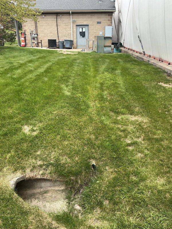 Conducted comprehensive site assessment for gas line installation serving outdoor mechanical equipment. Evaluated existing corroded piping infrastructure including blue-painted pump assembly with deteriorated flanges and oxidized connections, documented current system configuration with digital meter and pressure gauge components mounted on concrete pad adjacent to HVAC unit. Assessed backyard routing requirements from utility connection point through lawn area to equipment location, identified excavation pathway and measured distances for gas line extension to service mechanical systems at rear of residential structure.