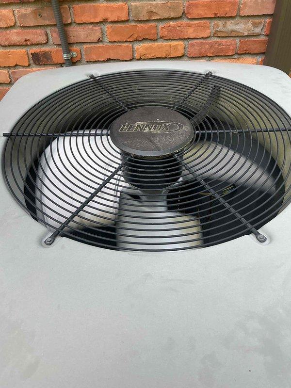 Completed comprehensive Gold AC inspection on a two-unit residential HVAC system with equipment over 10 years old. Performed thorough evaluation of Lennox outdoor condenser unit, including inspection of fan assembly, protective wire guard, and top-discharge configuration. Verified proper operation of both units, with air handler/coil located in attic and secondary unit in basement. Inspected condenser mounting, confirmed adequate clearance around unit, and assessed overall equipment condition. All systems verified operational at time of inspection.