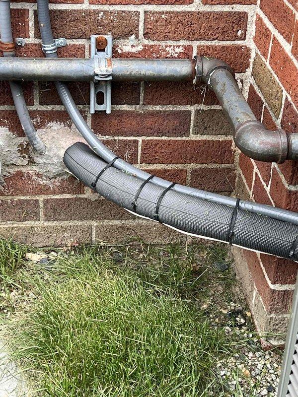Completed comprehensive Gold-level air conditioning inspection on 10+ year old system with air handler located in basement. Unit was operational at time of service. Performed thorough examination of indoor and outdoor components, including condensate drain line routing from utility sink area through exterior discharge point along foundation. Inspected exterior refrigerant lines, mounting hardware, and condensate piping secured to brick exterior with proper brackets and fasteners. Verified proper drainage function and documented system condition through photographic records. All components assessed for wear, proper installation, and compliance with manufacturer specifications.