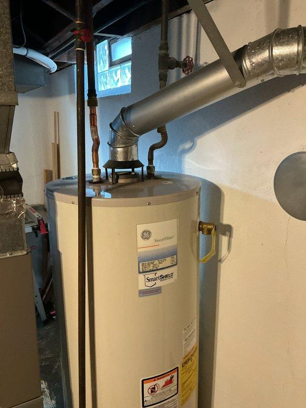 Completed installation of a 50-gallon GE SmartWater tanked water heater in basement utility room. Reconnected all water supply lines using copper piping with foam insulation, installed flexible connectors at base with shutoff valves, and properly vented unit through metal exhaust vent pipe connected to existing ductwork. All plumbing connections, pressure relief valve piping, and gas line hookups were completed to code specifications, with unit tested and verified operational.