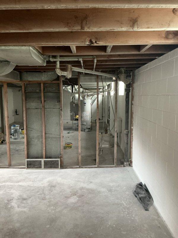 Conducted on-site plumbing assessment in residential basement utility area to provide free estimate for discussed plumbing work. Documented existing conditions including water heater installation, exposed piping systems, HVAC ductwork, and concrete block foundation walls to determine scope of required plumbing modifications and fixture installations.