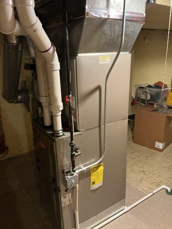 Completed comprehensive Gold AC inspection on 5-year-old single-unit residential HVAC system with equipment in working condition. Performed detailed system diagnostics including electrical testing with multimeter, recording voltage readings of 1296 to verify proper power supply to furnace and air handler assembly. Inspected indoor unit installation in basement utility area, confirming proper clearances, PVC condensate drain line connections, and flexible ductwork installation. Verified gas line connections, examined manufacturer specifications and safety labels, and assessed overall system operation. All components found functioning within normal parameters with no immediate service needs identified.