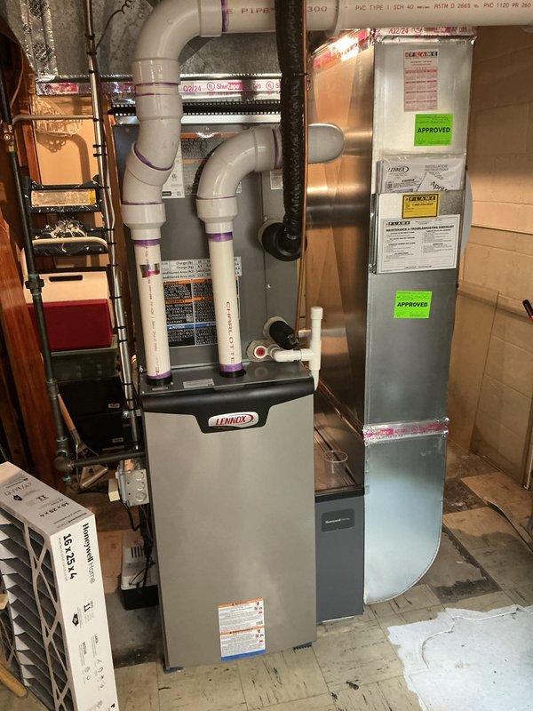 Completed comprehensive Gold AC inspection on single-unit Lennox system approximately one year old with air handler located in basement. System currently operational with thermostat set to heat at 70°F and cool at 82°F, displaying indoor temperature of 71°F with 39% humidity. Performed full visual inspection of furnace unit, air handler, PVC intake/exhaust venting, ductwork, and associated HVAC components in basement utility area. Verified proper operation of all equipment, checked connections, and documented system condition through photographic records. All components functioning within normal parameters at time of inspection.
