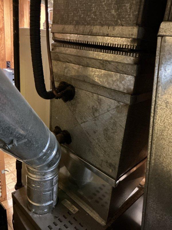 Provided estimate for complete HVAC system replacement in basement location. Existing air conditioning unit non-operational, with equipment age exceeding 10 years showing significant wear and dust accumulation. System assessment included evaluation of cylindrical furnace/air handler with natural gas fuel source, existing ductwork configuration including flexible metallic ducting, and overall installation conditions in confined basement space with exposed framing.